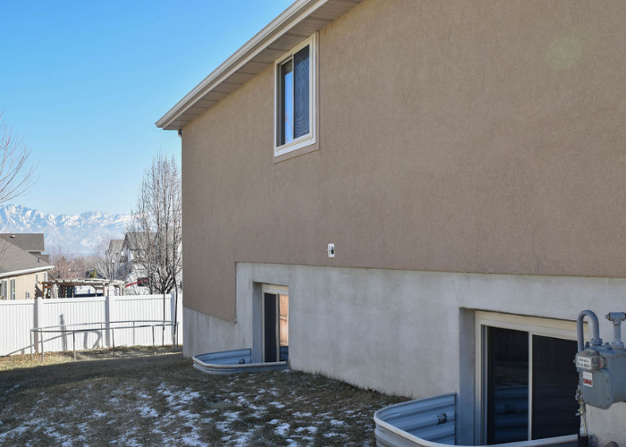 Stucco home with sliding windows and basement windows in West Valley City